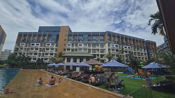Un hotel con piscina, varios balcones y una zona de juegos infantiles.