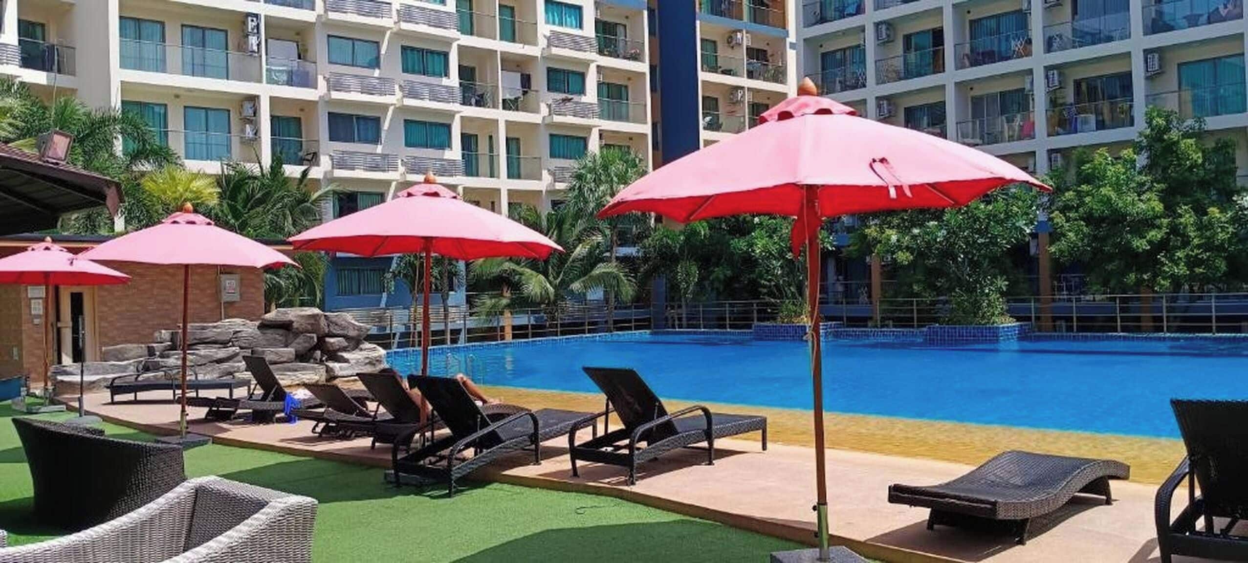 A hotel pool area with lounge chairs and umbrellas.