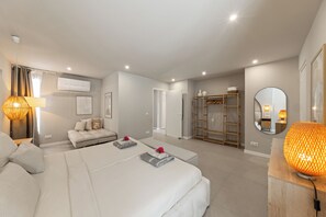 Ein modernes Hotelzimmer mit einem großen Bett, einer Sitzecke, einem Kleiderschrank und einem Badezimmer.