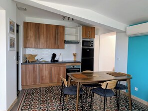 Eine kleine Küche mit Holdekor-Schränken, einer Mikrowelle, einem Kühlschrank und einem Essbereich mit einem gemusterten Boden.