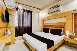 A hotel room with a bed, bedside table, lamp, phone, and an air conditioning unit. - Hotel O Vintage (New Delhi)