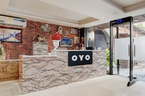 A reception desk with a marble design, a clock, and a sign that reads 'OYO'. - Hotel O Vintage (New Delhi)