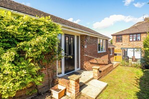 A residential property with a brick exterior, a front door with a glass panel, and a small front yard with steps leading to the entrance. - One Bed Bungalow Sleeps 4 - Garden - Wifi & Tv (Andover)