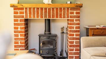 A brick fireplace with a black stove, a wooden mantel, and a decorative white figure on top.