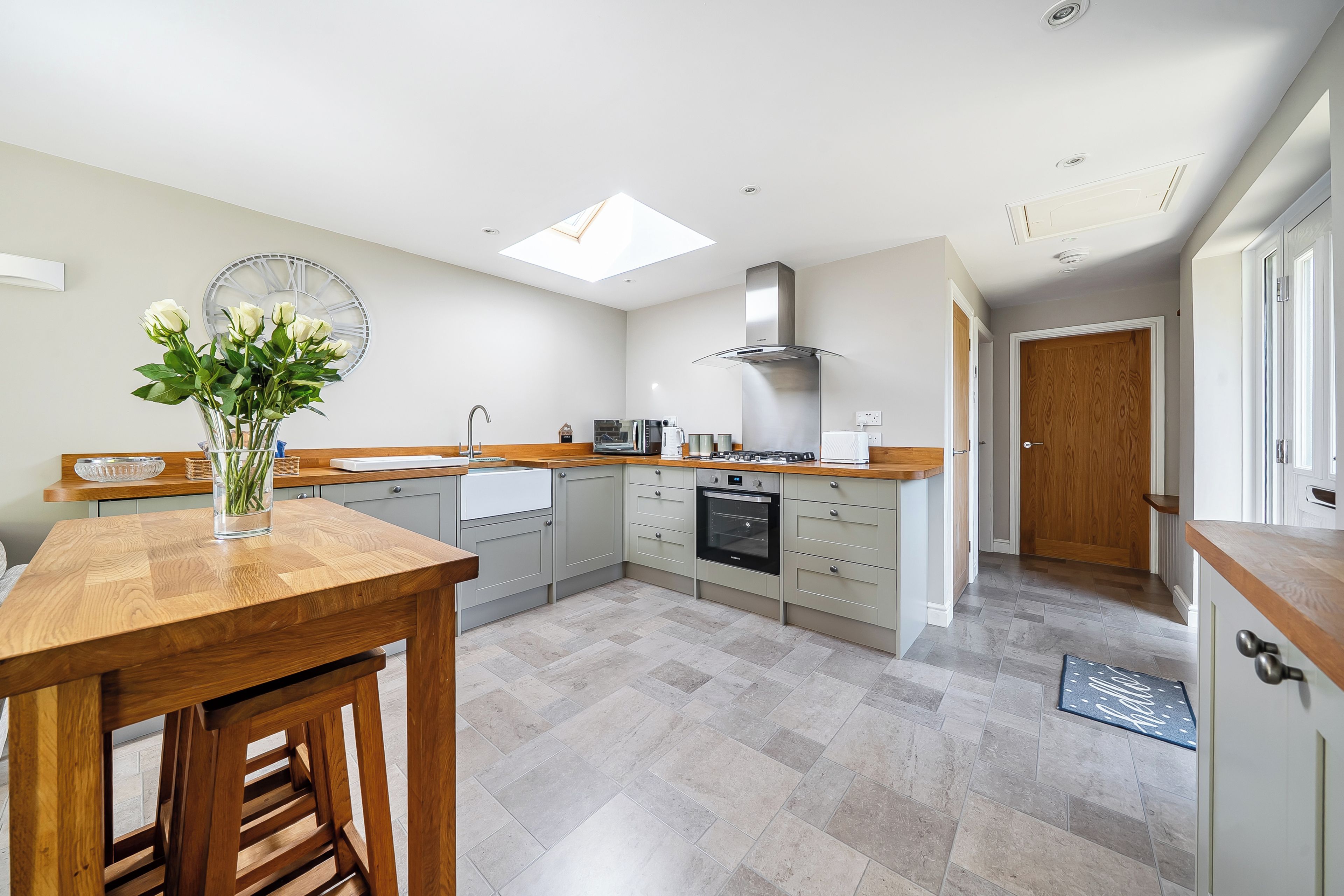 A modern kitchen with a skylight, a dining area with a wooden table, and a view of the hallway.