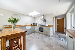 A modern kitchen with a skylight, a dining area with a wooden table, and a view of the hallway. - One Bed Bungalow Sleeps 4 - Garden - Wifi & Tv (Andover)