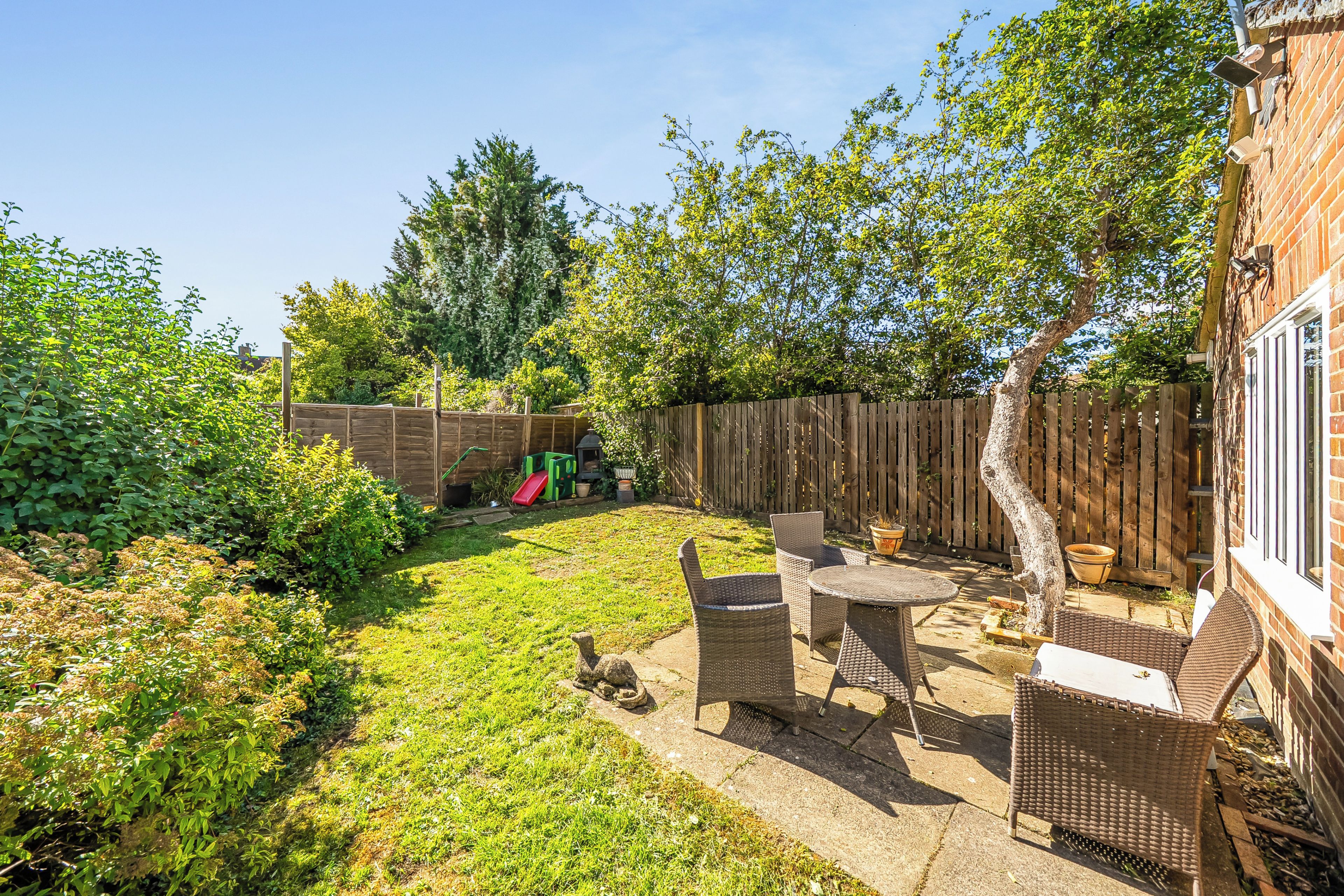 A backyard with a patio, a wooden fence, and a brick wall.