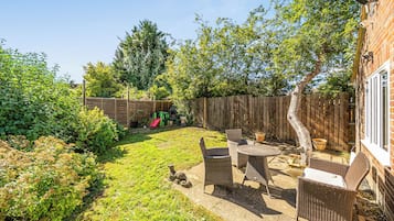 A backyard with a patio, a wooden fence, and a brick wall.