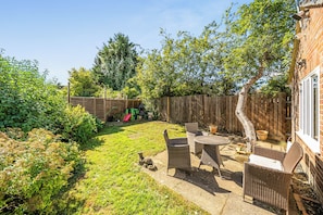 A backyard with a patio, a wooden fence, and a brick wall. - One Bed Bungalow Sleeps 4 - Garden - Wifi & Tv (Andover)