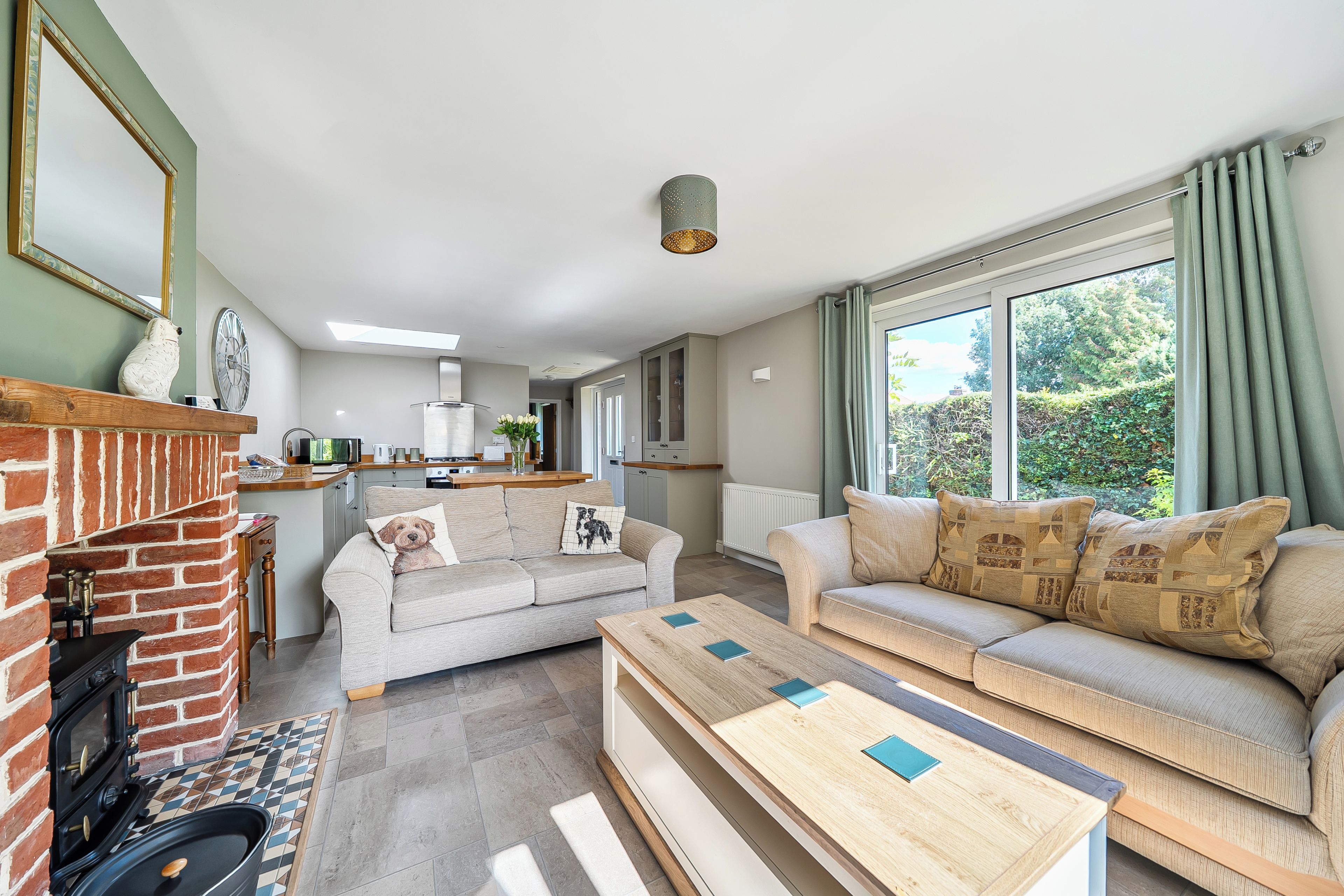 Ein modernes Wohnzimmer mit Kamin, einer Sofagarnitur, einem Couchtisch und Blick ins Freie.