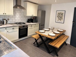 A modern kitchen with white cabinetry, a gas stove, a microwave, and a refrigerator.