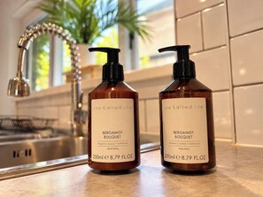Dos botellas de loción de manos Aroma de Bergamota sobre una encimera de cocina.