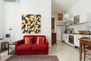 A living room with a red sofa, a patterned rug, and a wall art piece. - A comfortable and bright 64 square meters apartment, perfect for four people, located on the first floor of a building with an elevator (NOT accessible to people with disabilities).The property is in a highly strategic location for exploring the city, si (Milan)