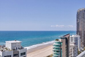 Eine Küstenstadt mit hohen Gebäuden, einem Strand und wolkenlosem Himmel.
