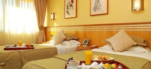 Quarto de hotel com duas camas, um suporte para café da manhã e uma mesa de cabeceira com telefone.