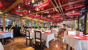 A restaurant interior with tables set for dining, wooden flooring, and a modern ceiling design. - Hotel Ankara (Vina del Mar)
