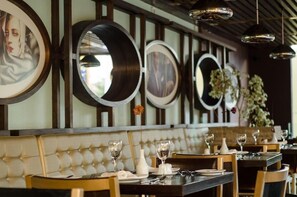 A restaurant interior with round mirrors on the wall, cushioned seating, and dining tables set with glasses and cutlery. - Hotel Ankara (Vina del Mar)