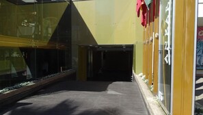 A corridor with a glass wall on one side and a yellow wall on the other, leading to a door. - Hotel Ankara (Vina del Mar)