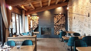 Ein Restaurant mit Holzbalken, Steinwänden und karierten Stühlen. Die Tische sind mit Gläsern und Besteck gedeckt.