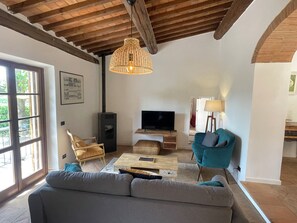 Un saló amb un sofà, una televisió, una taula baixa de fusta i una làmpada penjant.