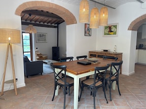 Un coin repas avec une table en bois et des chaises noires, un lampadaire et une cheminée.