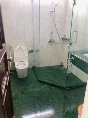 A bathroom with a toilet, a shower enclosure, and a glass shower door. - Seven Thao Dien (Ho Chi Minh Municipality)