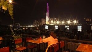 Pessoa sentada à mesa com vista para o horizonte urbano à noite.