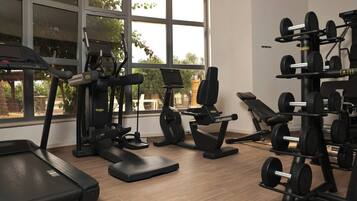 A gym with treadmills, weight benches, and free weights.
