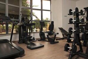 Ein Fitnessstudio mit Laufbändern, Gewichtbänken und Kurzhanteln.