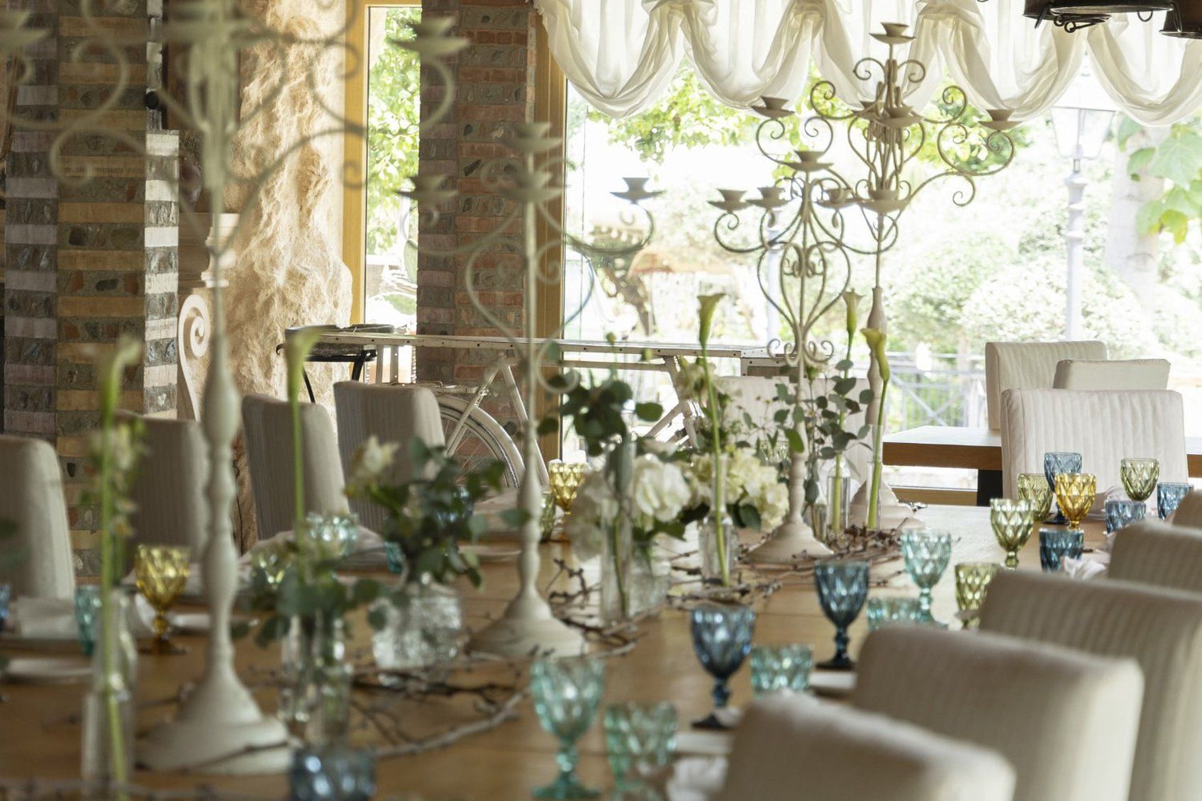A dining area with a brick wall, a bicycle, and a chandelier.