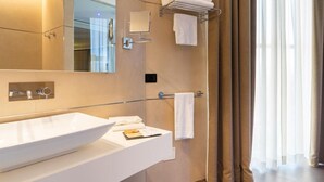 Een moderne badkamer met een groot wastafel, spiegel, handdoekhouder en douchegordijn.