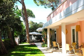Un patio al aire libre soleado con juegos de comedor y una zona de estar cubierta.
