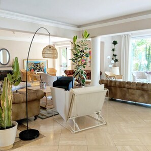 Amplia sala de estar con un sofá, un sillón y una planta grande en maceta.