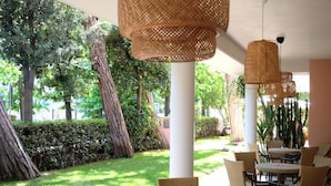 An outdoor seating area with wicker furniture and hanging lamps. - Hotel Piccolo Mondo (Camaiore)