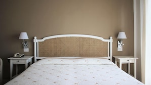 A neatly made bed with a white headboard and a floral-patterned bedspread. There are two bedside tables, each with a lamp and a phone. - Hotel Piccolo Mondo (Camaiore)
