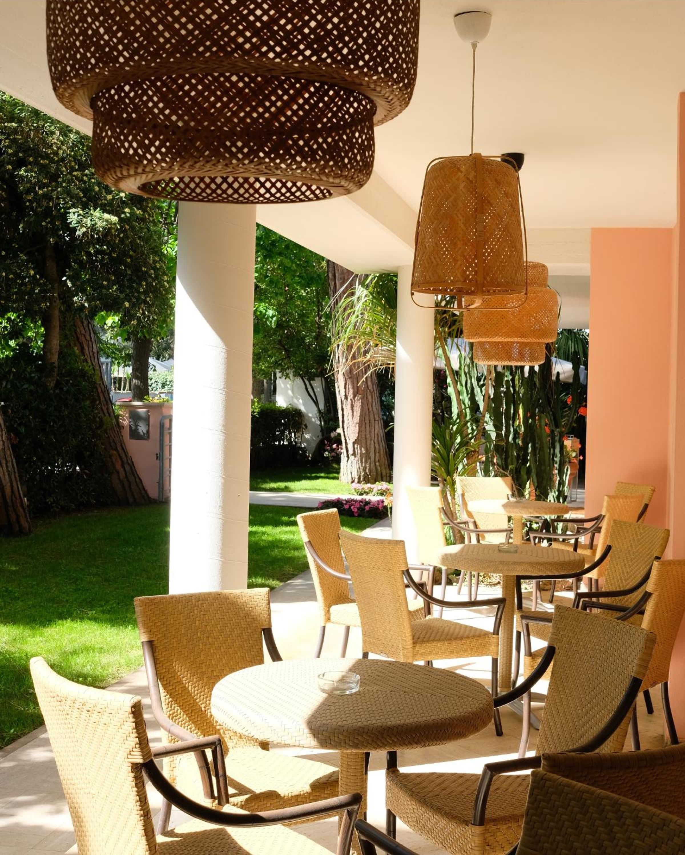 An outdoor patio with wicker furniture and hanging lamps.