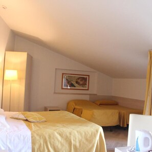 A hotel room with two beds, a bedside table, a lamp, a framed picture on the wall, and a coffee maker. - Albergo Sole (San Zeno di Montagna)