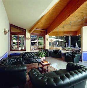 Amplia sala de estar con sofás de cuero, una mesa de centro y ventanas grandes con vistas al exterior.