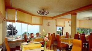 A restaurant with multiple tables, each set with plates, cutlery, and a bottle of wine. - Albergo Sole (San Zeno di Montagna)