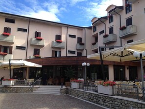 Un hotel con terraza al aire libre, escalones de piedra y balcones con jardineras de flores.