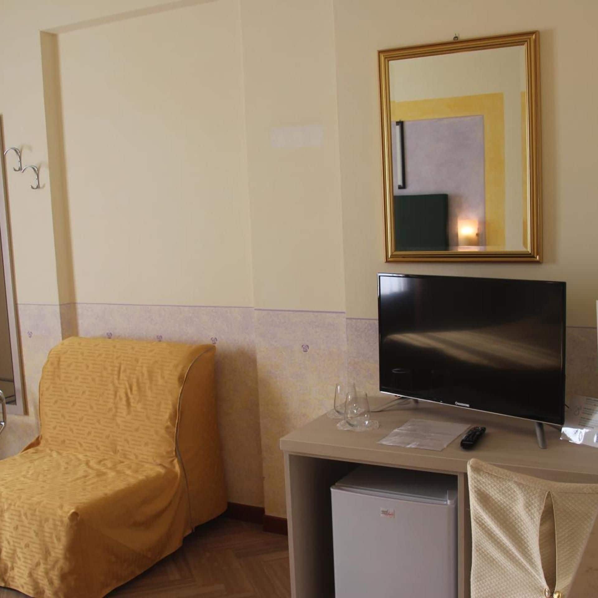 Ein Hotelzimmer mit einem Bett, einem Schreibtisch mit Fernseher und einem kleinen Kühlschrank.