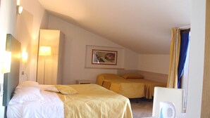 A hotel room with two beds, a desk with a chair, a lamp, and a painting on the wall. - Albergo Sole (San Zeno di Montagna)