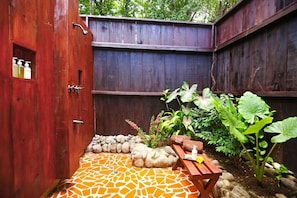 Une porte en bois avec une petite fenêtre, un chemin de pierres et un banc en bois avec un coussin.