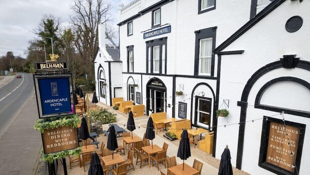 An outdoor seating area with tables and chairs, a sign for the Ardencaple Hotel, and a street sign for Belhaven. - Ardencaple (Helensburgh)