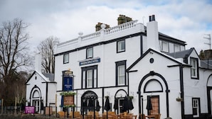A white building with black trim, named 'ARDENCAPLE HOTEL,' featuring a traditional architectural style with arched windows and a stone facade. - Ardencaple (Helensburgh)