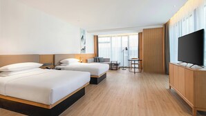 Habitación de hotel con dos camas, televisión, escritorio y una silla.