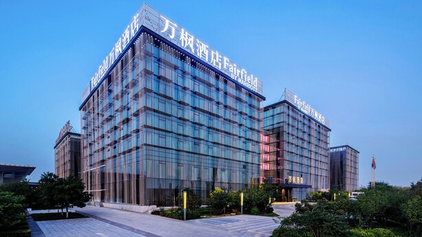 Un hotel moderno con un letrero llamativo, amplios ventanales de vidrio y un área exterior bien cuidada.
