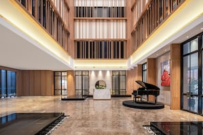 A spacious lobby with a grand piano, a reception desk, and a large window offering a view. - Fairfield By Marriott Taiyuan South (Taiyuan)