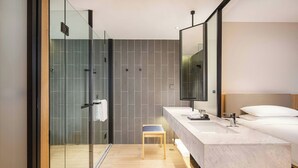 Un baño moderno con cabina de ducha de vidrio, un banco de madera, un espejo grande y un lavamanos de mármol.