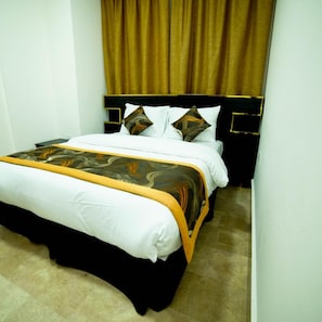 A hotel room with a bed, a headboard, and curtains. - Oyo 112 Star Emirates Downtown (Salalah)